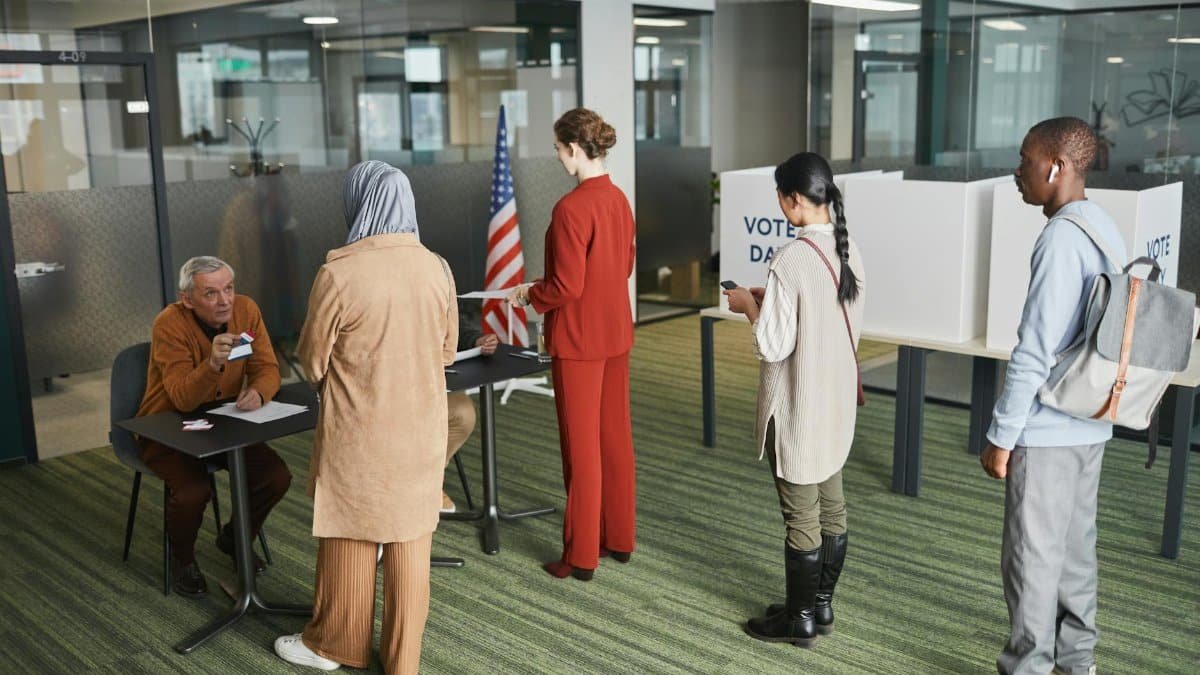Diverse group of voters lining up at an indoor polling station on election day.