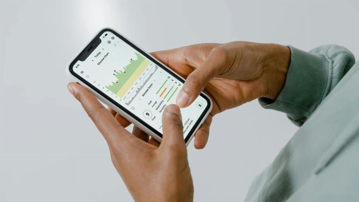 Close-up of hands holding a smartphone showing a health tracking app with charts and data.