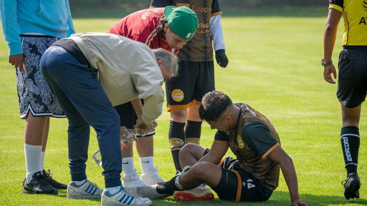An injured soccer player receiving on-field medical attention during a game.