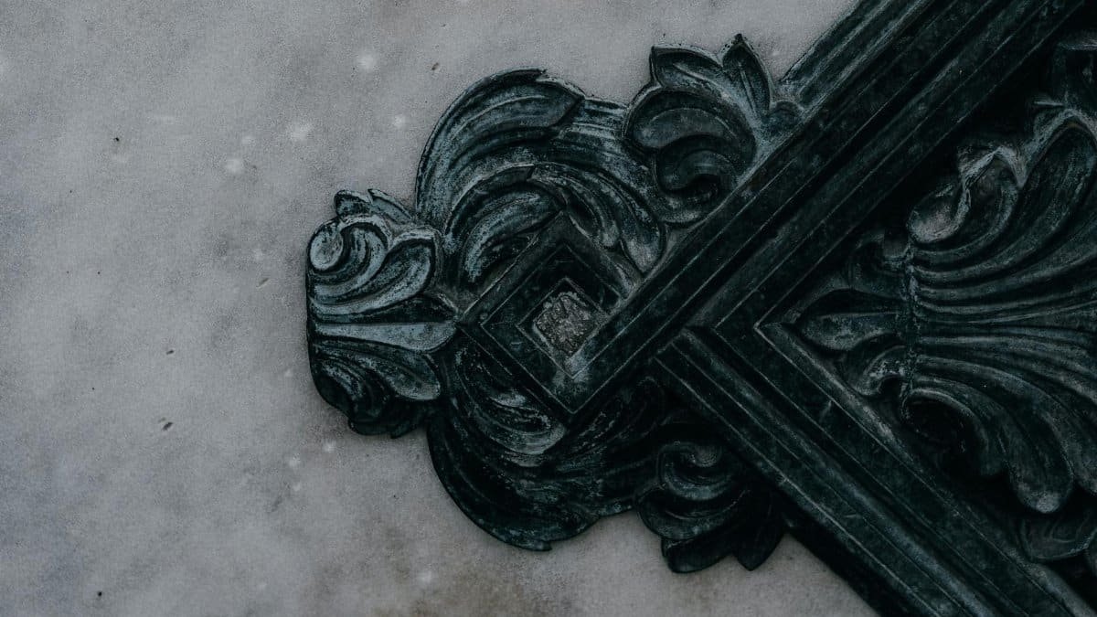 Intricate dark gray ornate carving on a textured concrete surface, showcasing detailed craftsmanship.