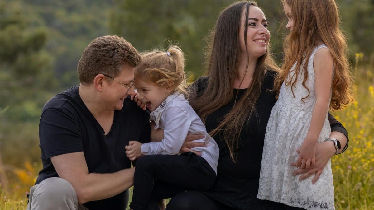 A joyful family enjoying a moment outdoors with their daughters.