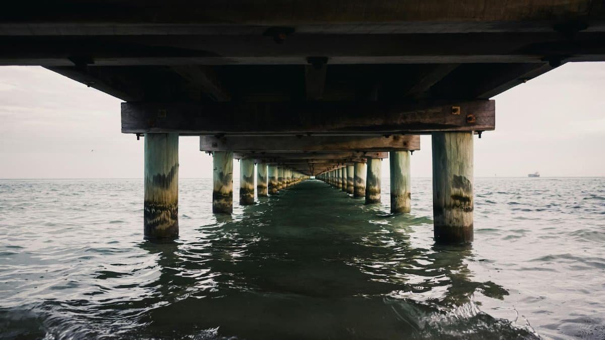Tranquil ocean waves beneath a wooden pier, creating a peaceful coastal scene.