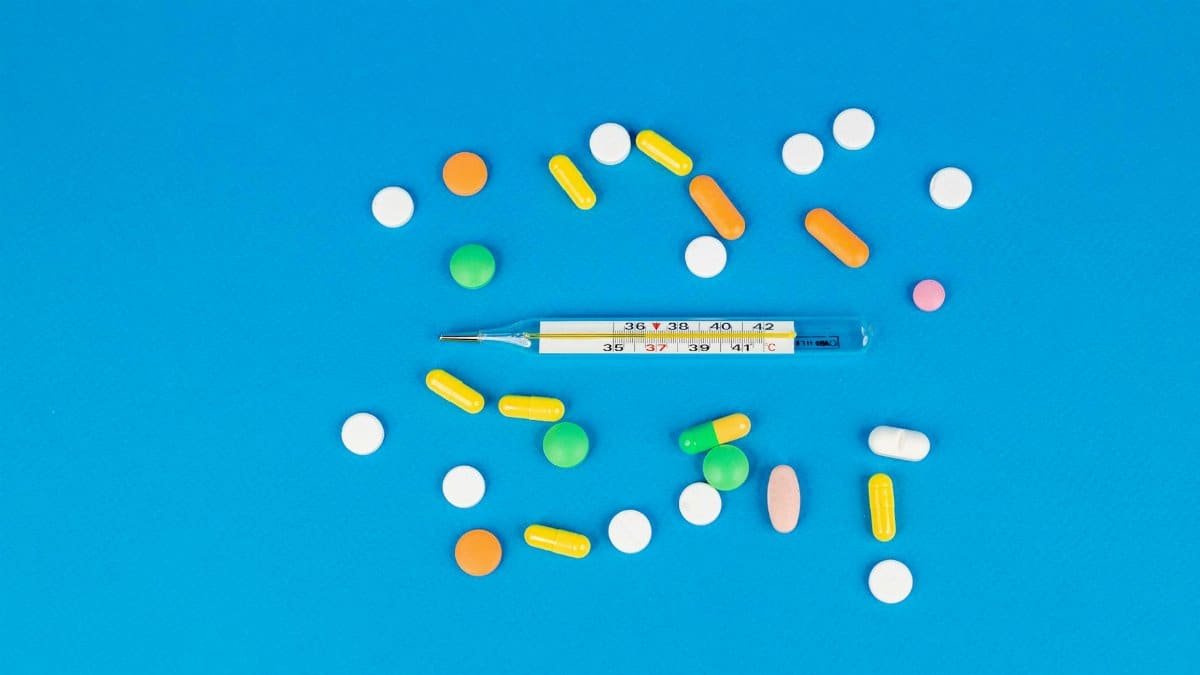 Vibrant pills and a thermometer arranged on a blue backdrop. Perfect for health and medicine themes.