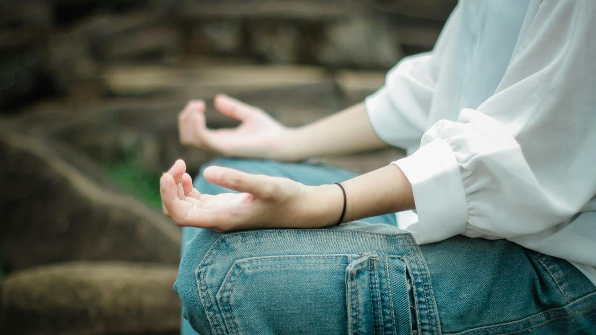 Person meditating outdoors, focusing on peace and relaxation.