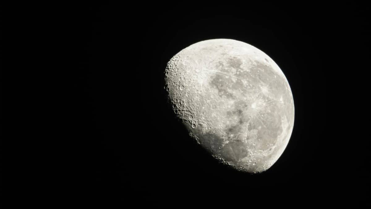Detailed view of the Moon phase with visible craters against a dark night sky.