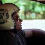 Man wearing a Ruta 40 helmet driving a car, looking into the distance.