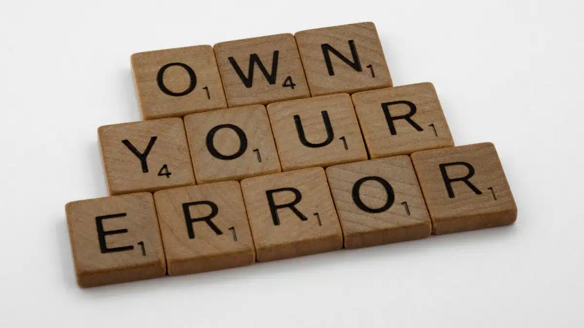 Scrabble tiles forming the phrase 'OWN YOUR ERROR'. Great for concepts of accountability and motivation.