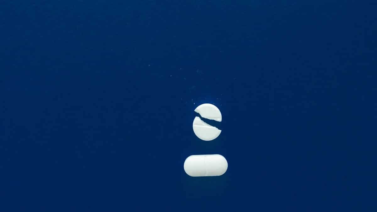 Broken pill with copy space on a blue background, symbolizing healthcare or medication concepts.