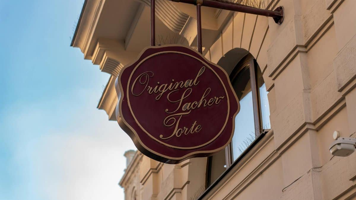 Detailed view of the Original Sacher Torte sign against a Viennese building facade.