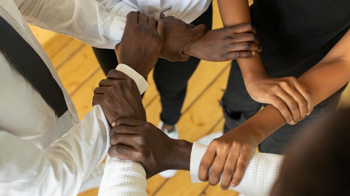 Close-up of diverse hands in a circle, symbolizing teamwork and unity.