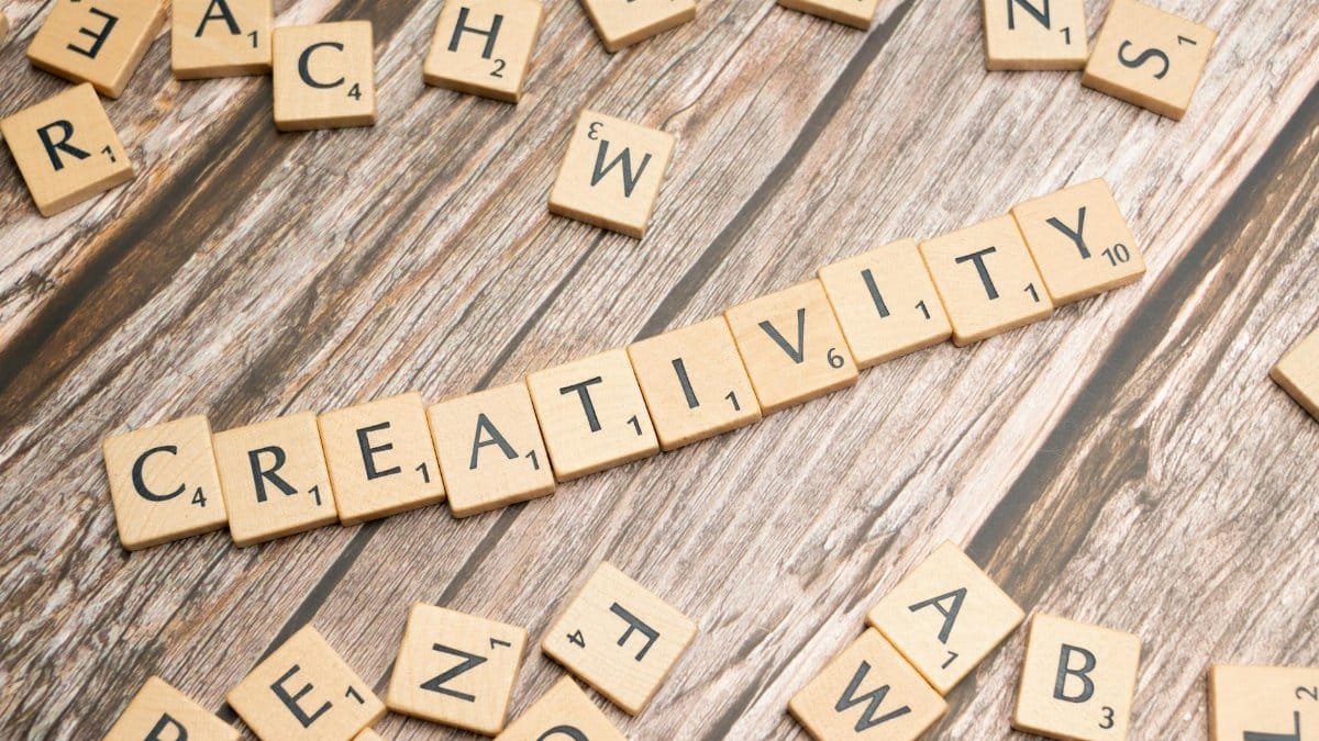 Wooden letter tiles spelling 'creativity' on a rustic wooden background.