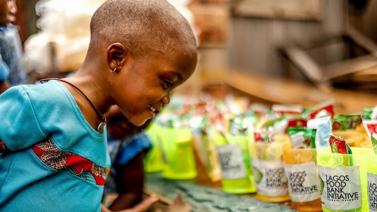 A smiling child engages with the Lagos Food Bank Initiative, showcasing joy and community support.