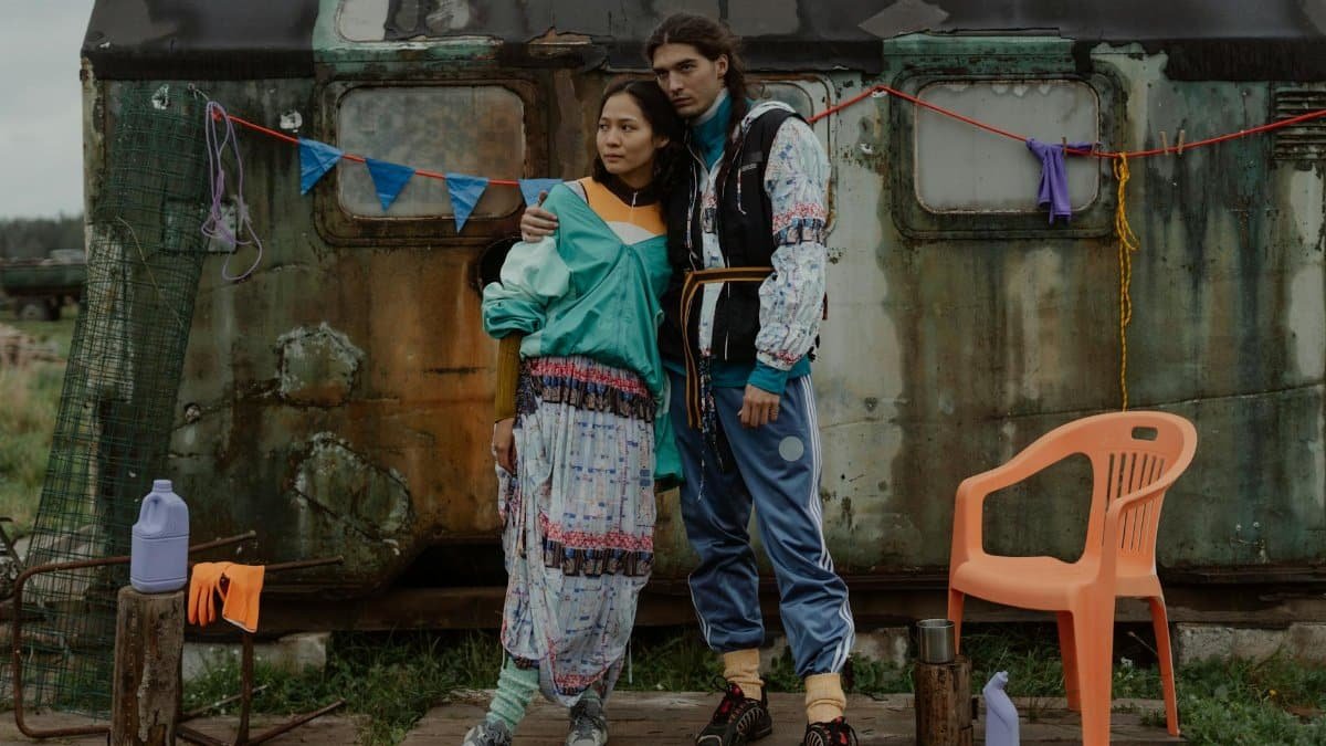 A couple in vibrant attire posing outdoors, embracing a nomadic lifestyle vibe.
