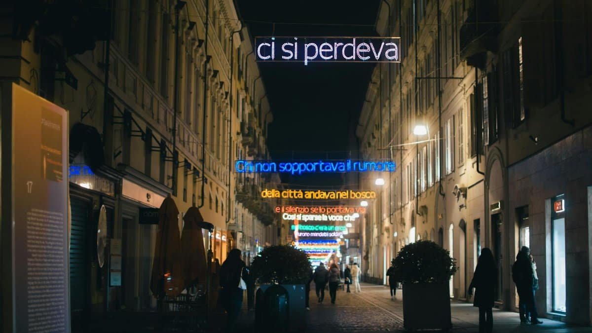 A bustling urban street illuminated by neon signs and streetlights, capturing the evening ambiance.