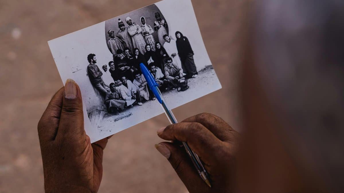Hands holding a vintage photograph with a pen, capturing memories in Tiznit, Morocco.