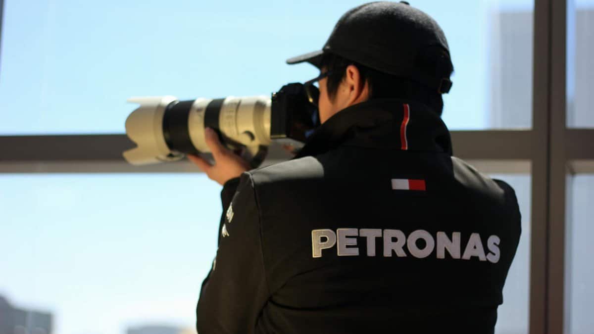 Photographer using a telephoto lens to capture an urban scene from a window view.