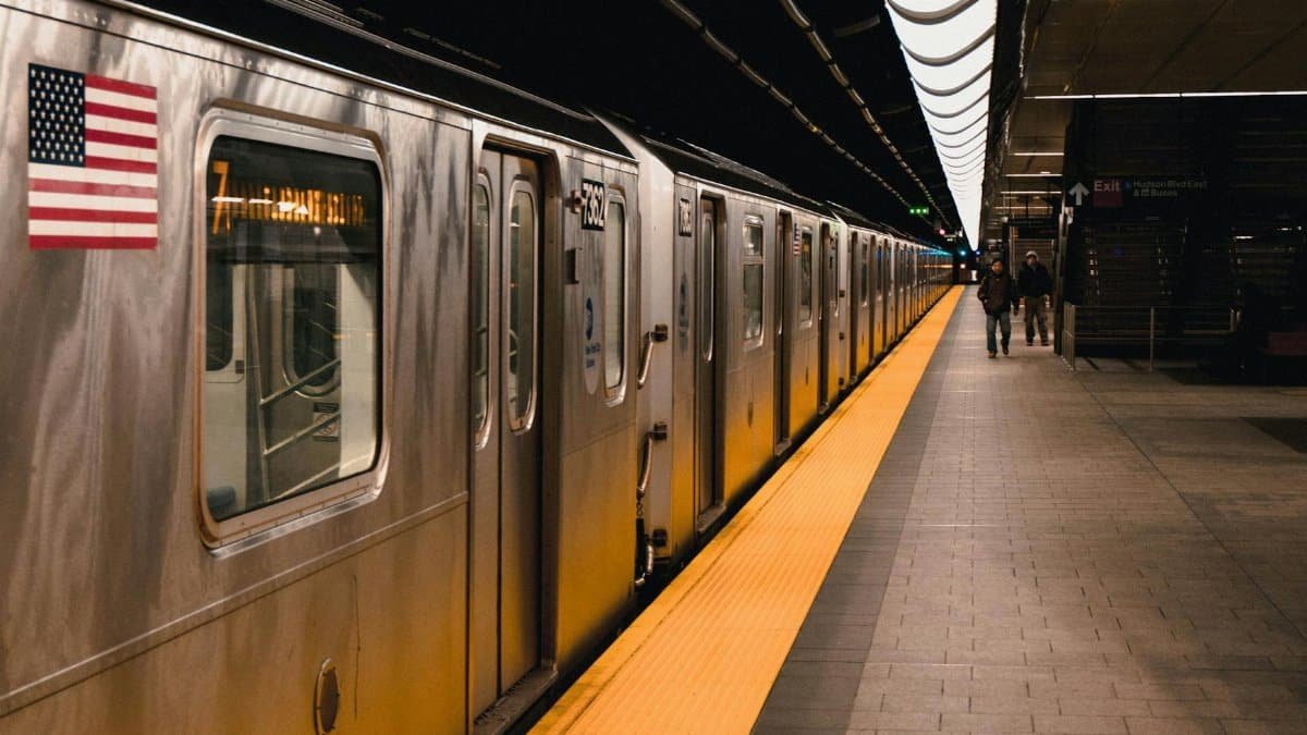 Image of a New York subway train at an underground station platform with an American flag.