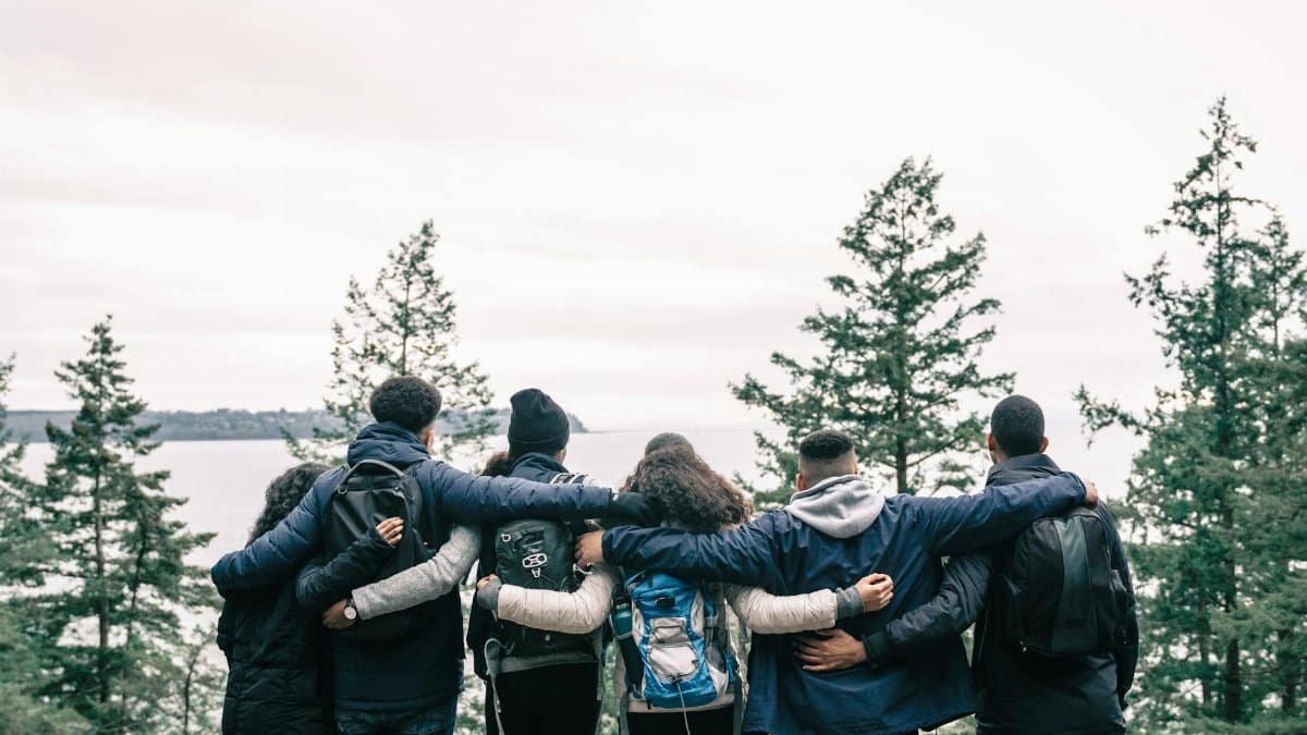 Friends embrace while standing on a scenic cliff, symbolizing unity and adventure.
