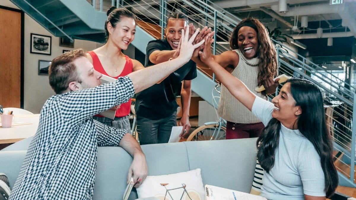A multicultural office team high-fiving and celebrating a successful collaboration.