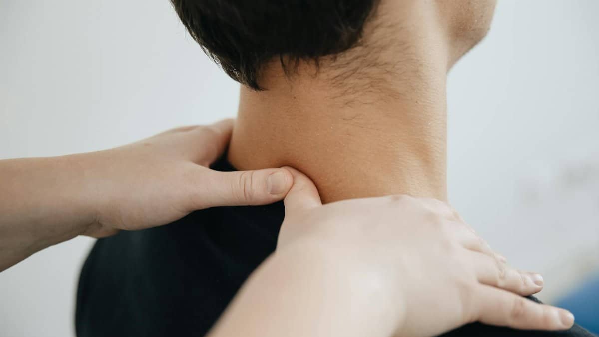 Close-up of a physiotherapist providing neck massage for pain relief in a clinic setting.
