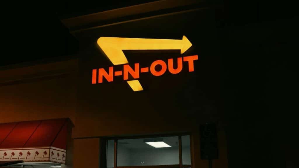 Bright neon In-N-Out sign glowing at night outside a restaurant in California.