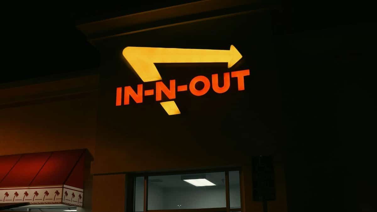 Bright neon In-N-Out sign glowing at night outside a restaurant in California.