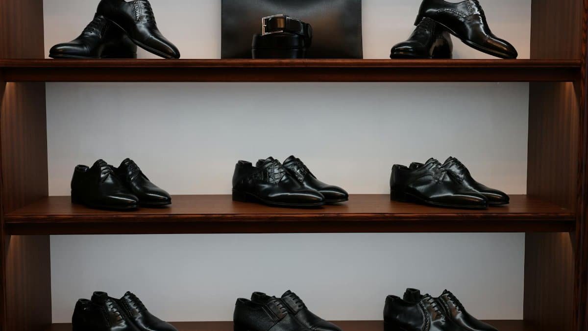 A stylish display of black leather shoes and accessories on wooden shelves in a store.