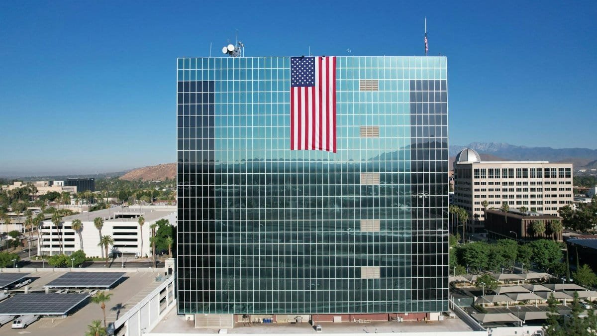 Stunning aerial shot of the Riverside County Administrative Center with American flag, showcasing urban landscape and architecture.
