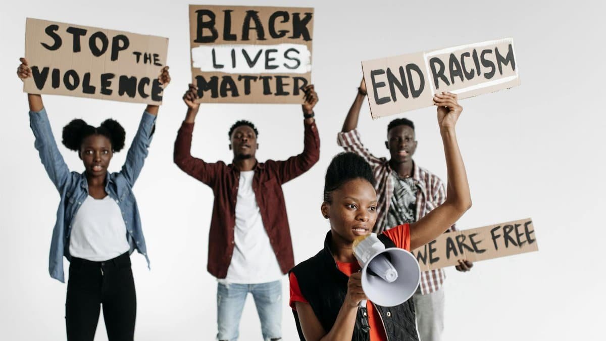 A diverse group of individuals holding activism signs against racism and violence.