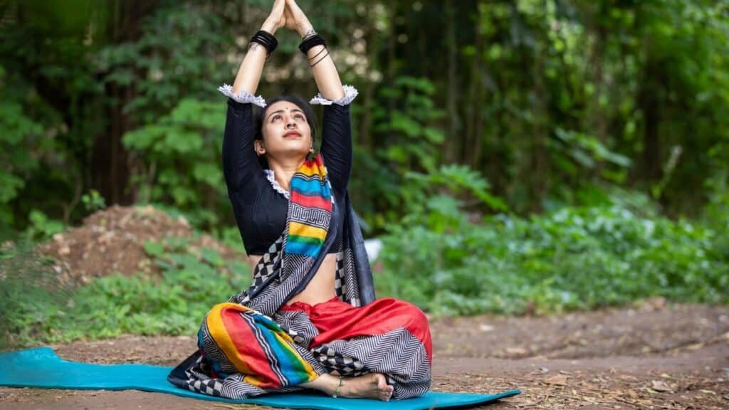 South Asian woman practicing yoga outdoors, embracing wellness and mindfulness in vibrant attire.
