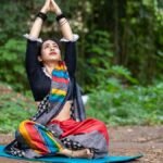 South Asian woman practicing yoga outdoors, embracing wellness and mindfulness in vibrant attire.