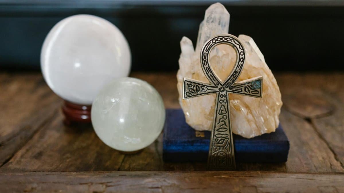 A symbolic Ankh with crystal spheres represents mystic energy on a wooden surface, ideal for spiritual themes.