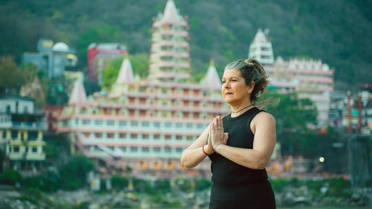A woman doing yoga near the iconic Tera Manzil Temple in Rishikesh, India.