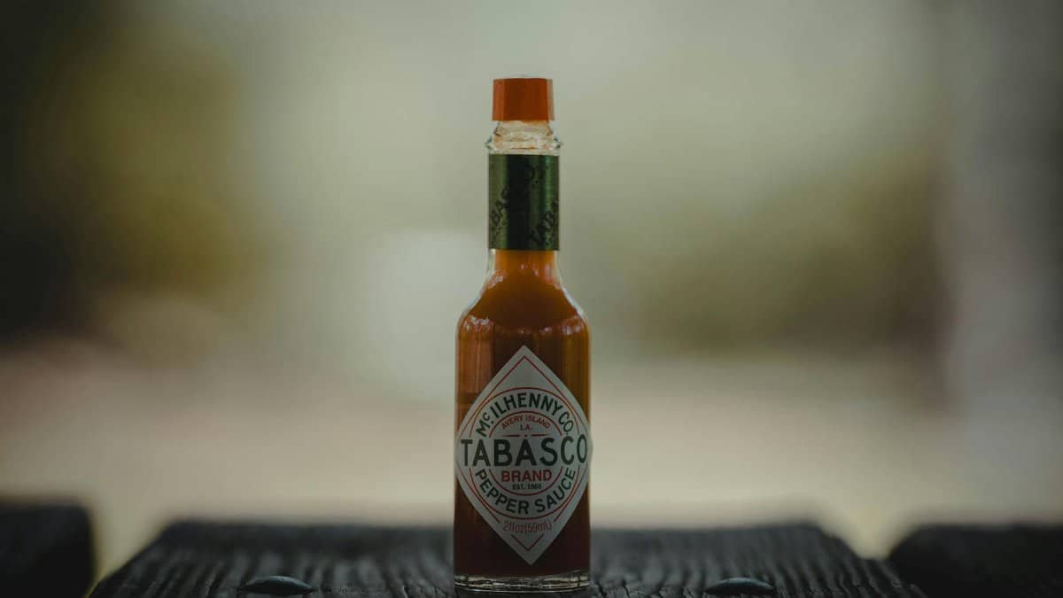 Close-up of a Tabasco sauce bottle on a wooden surface, emphasizing its spicy essence.