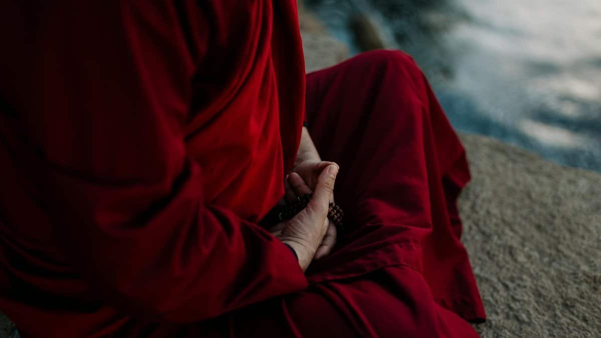 A monk in traditional robe holding prayer beads, embodying spirituality and tranquility.