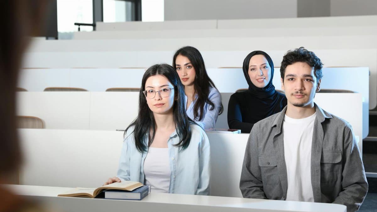 Group of diverse university students attending a class session in a modern lecture hall.