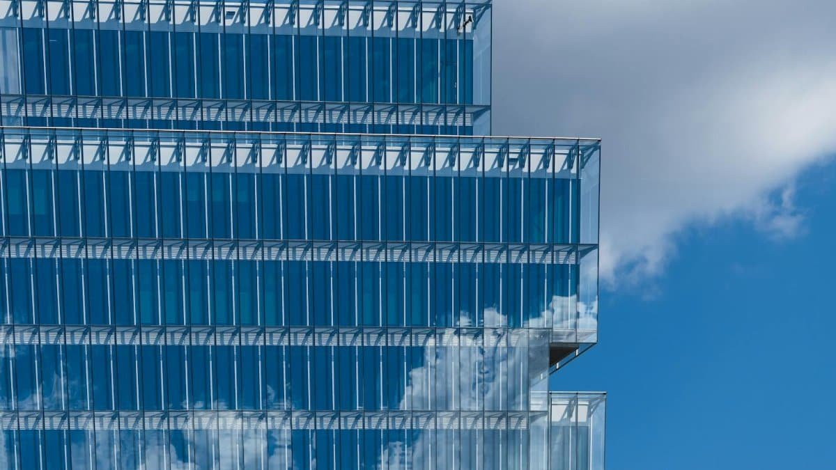 A striking image of a modern glass building reflecting the blue sky and clouds, showcasing architectural elegance.