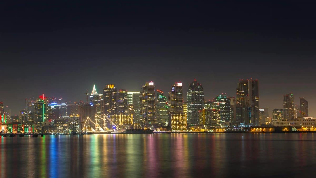 A serene night view of San Diego's illuminated skyline reflecting on calm water.