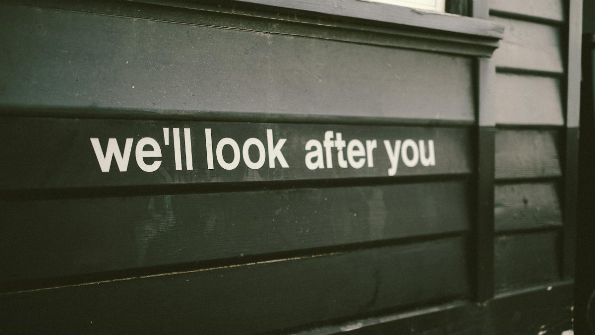 Close-up of a wooden facade with the positive message 'We'll look after you.'