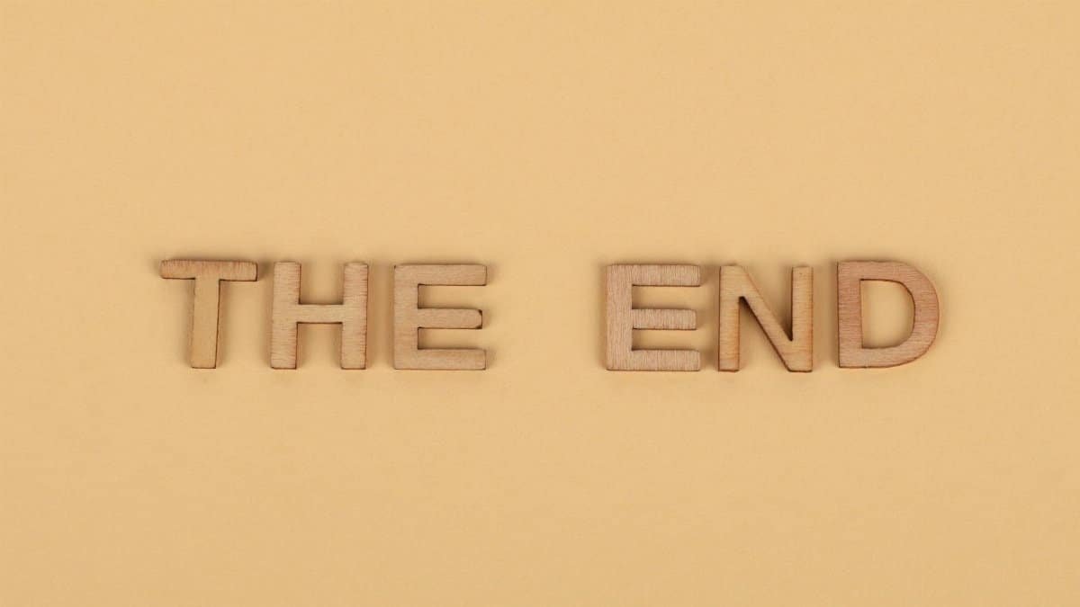 Wooden letters spelling 'The End' on a plain beige background, perfect for endings.