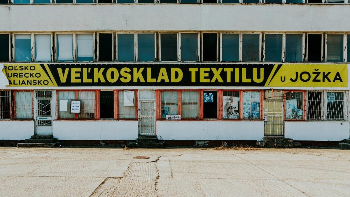 Old textile warehouse with a weathered facade and signage in an urban location.