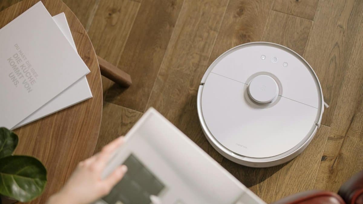 A sleek robot vacuum cleaner operating on a wooden floor, symbolizing modern home technology.