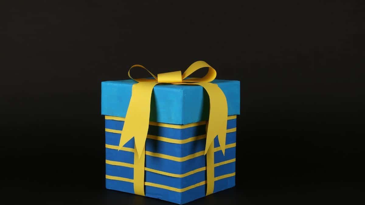 Vibrant blue gift box wrapped in yellow ribbon on black background for celebrations.