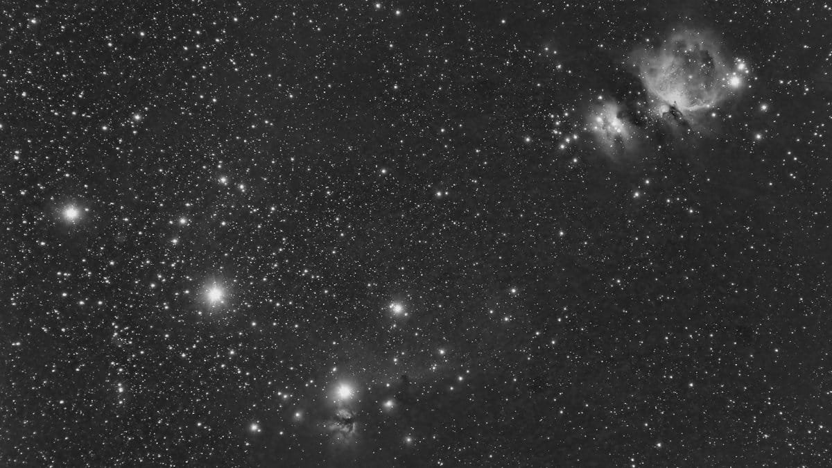 A breathtaking grayscale astrophotograph depicting the Orion and Flame Nebulas set against a starry night sky.