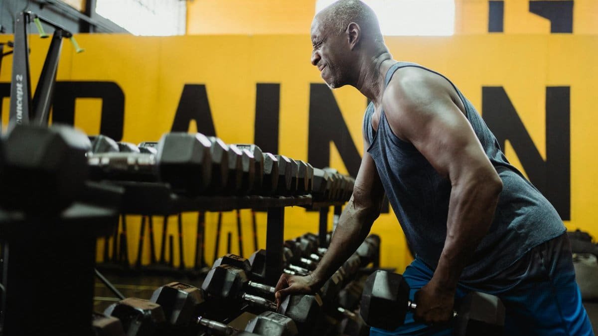 Man lifting dumbbells in gym focusing on strength training and fitness.