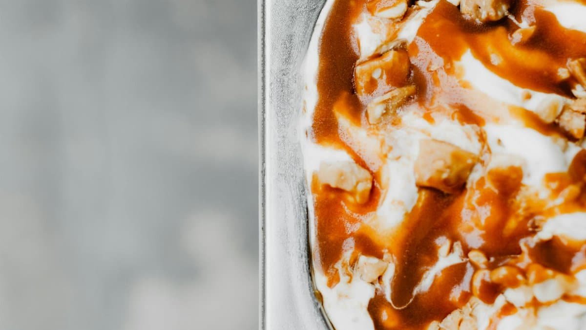 Close-up of creamy ice cream topped with rich caramel sauce and nuts, perfect for dessert lovers.