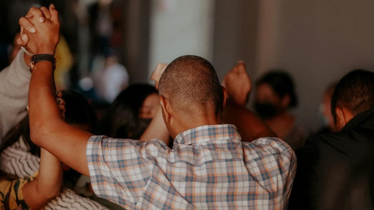 A group of diverse adults holding hands in a prayer circle, fostering unity and connection.