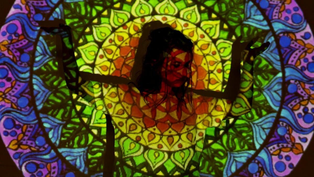 A colorful and vibrant psychedelic projection on a woman posing in a studio setting, embracing spiritual themes.
