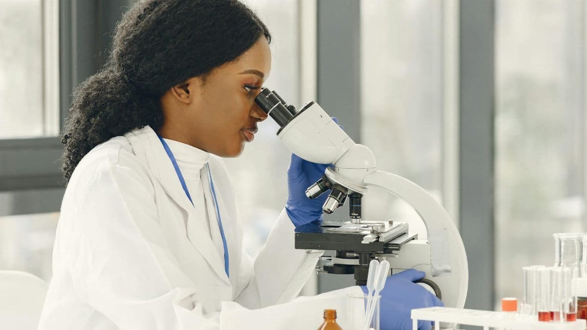 A female scientist in a lab coat using a microscope in a modern laboratory setting.