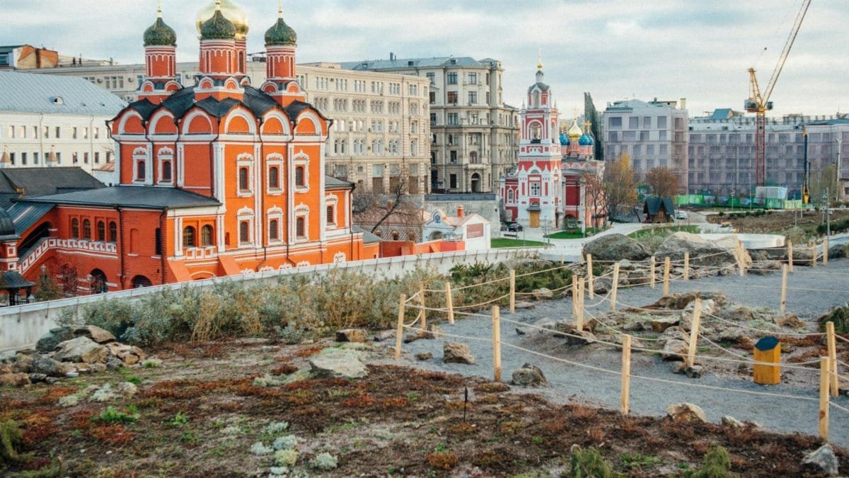Scenic view of a red historic church surrounded by urban buildings and construction in a city.